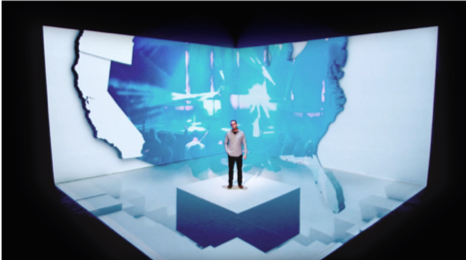 Man standing on stage with 3D projection mapping technology showing a partial map of the United States