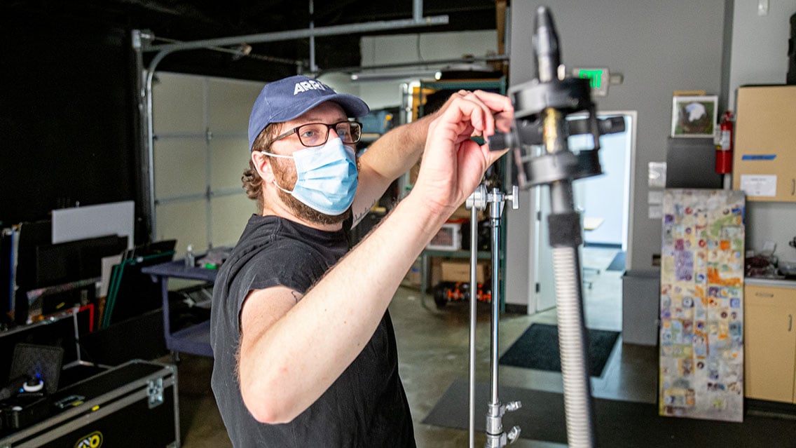 Director of Photography in a mask setting up camera equipment for a video production shoot