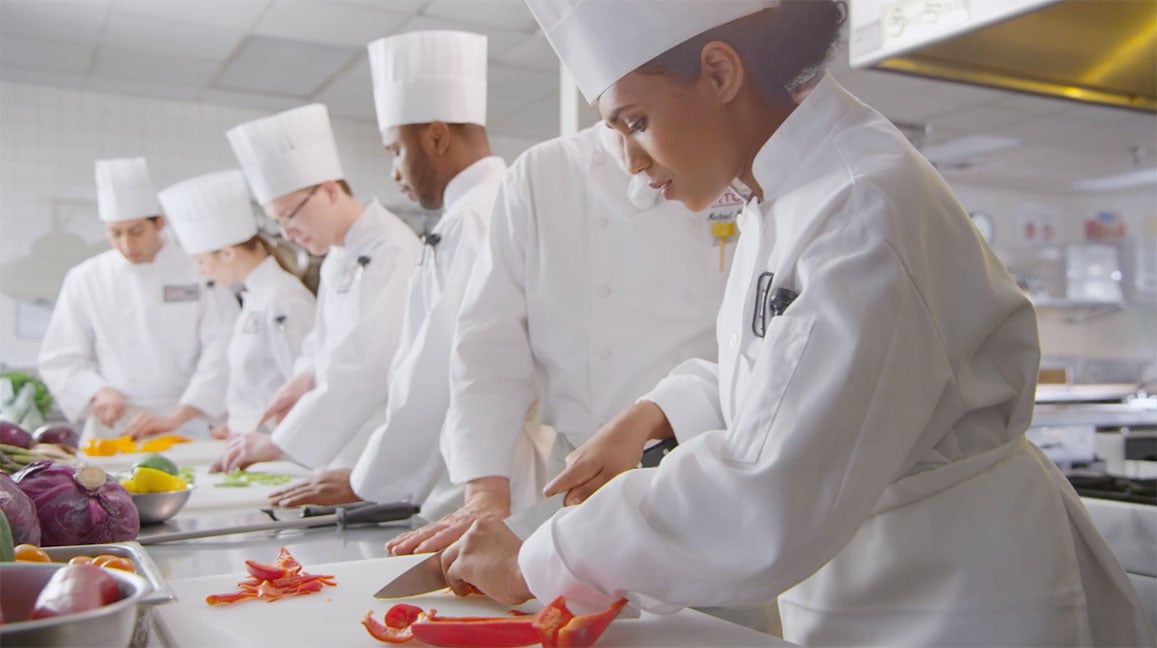 Female chef in live action video cutting bell peppers