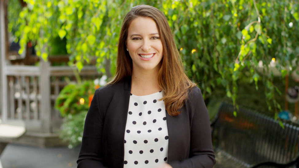 Interview subject looking directly into camera with lush green background