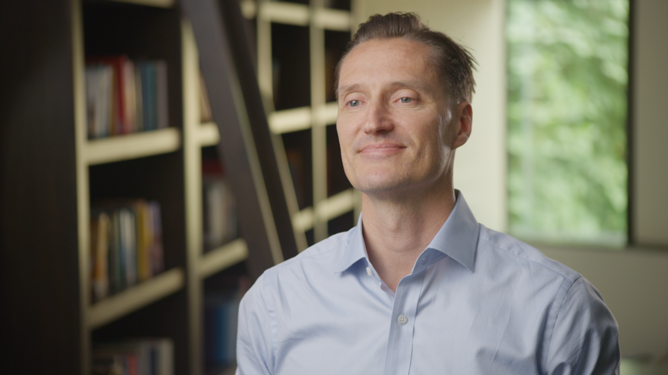 Middle-aged man sitting in library setting looking off camera in organic setting