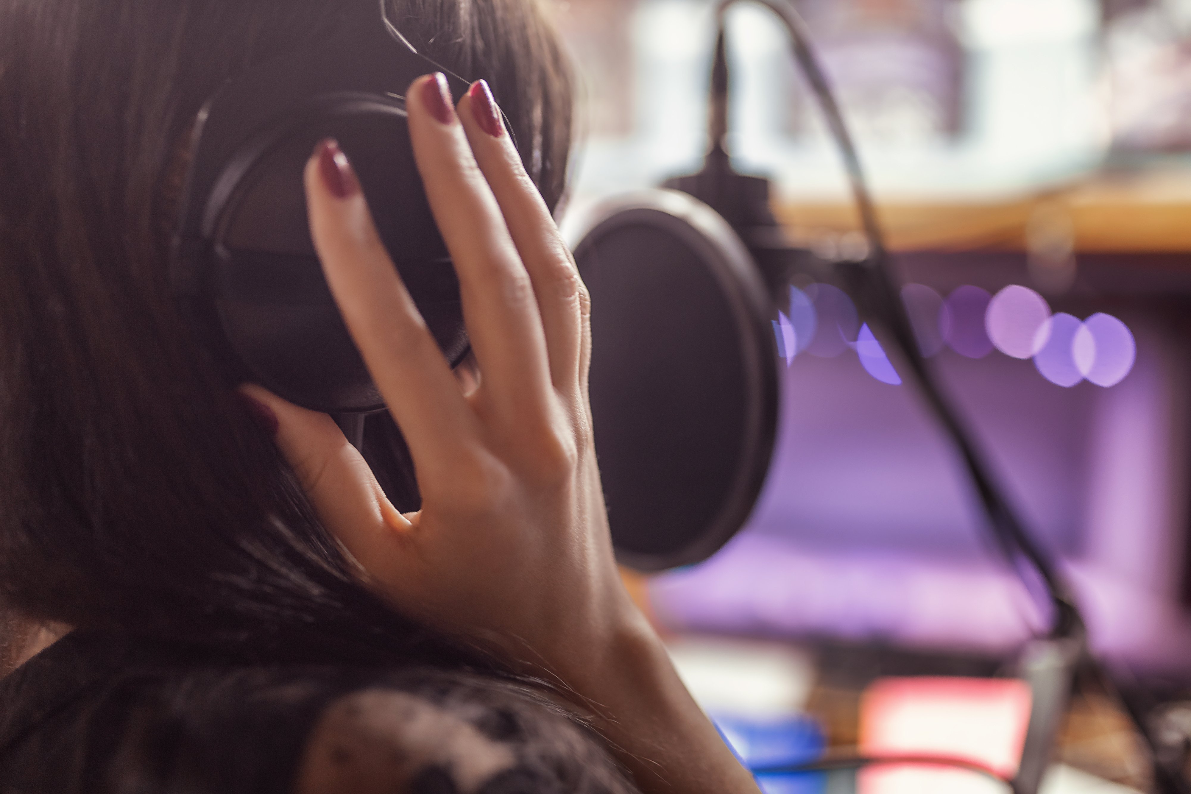 Woman with her hands on her headphones recording voiceover track