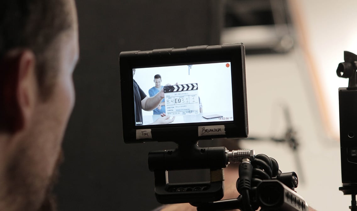 Camera operator looks at video monitor before rolling on set during a video production shoot at VMG Studios