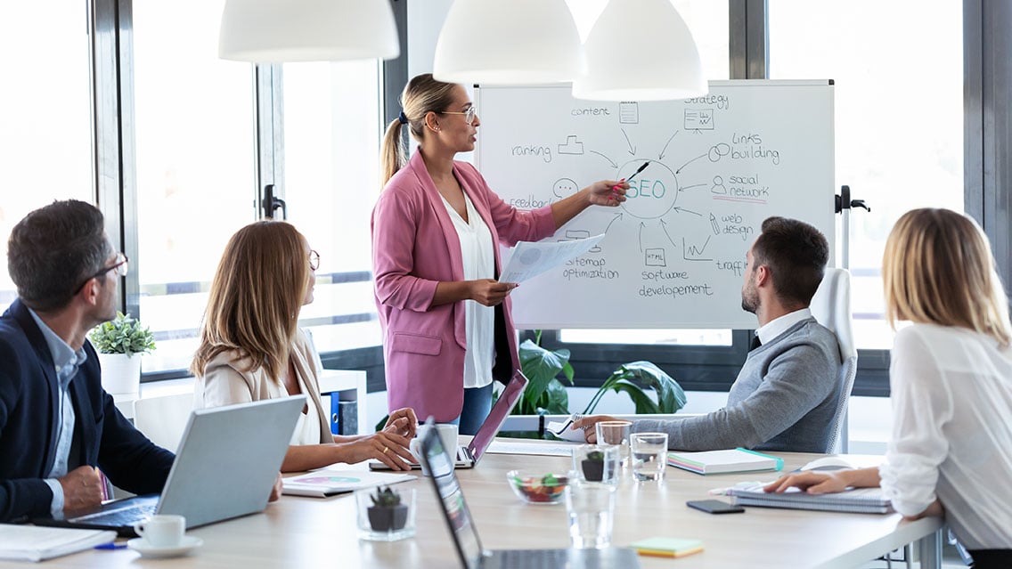 Team of marketers in a B2B company going over a content marketing strategy in a bright, open office space