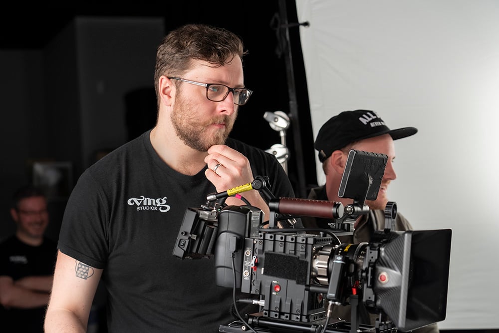 Director of Photography and cinematographer looks at his camera, considering the shot