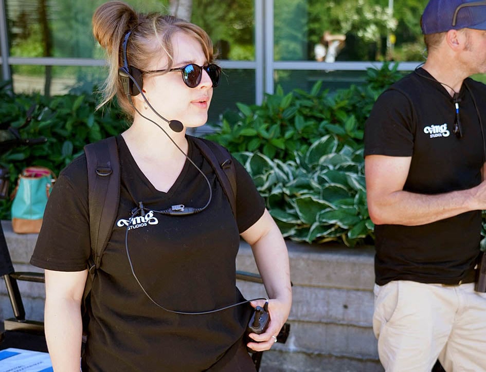 Production assistant wearing a headset and talking on a walkie-talkie during a video shoot