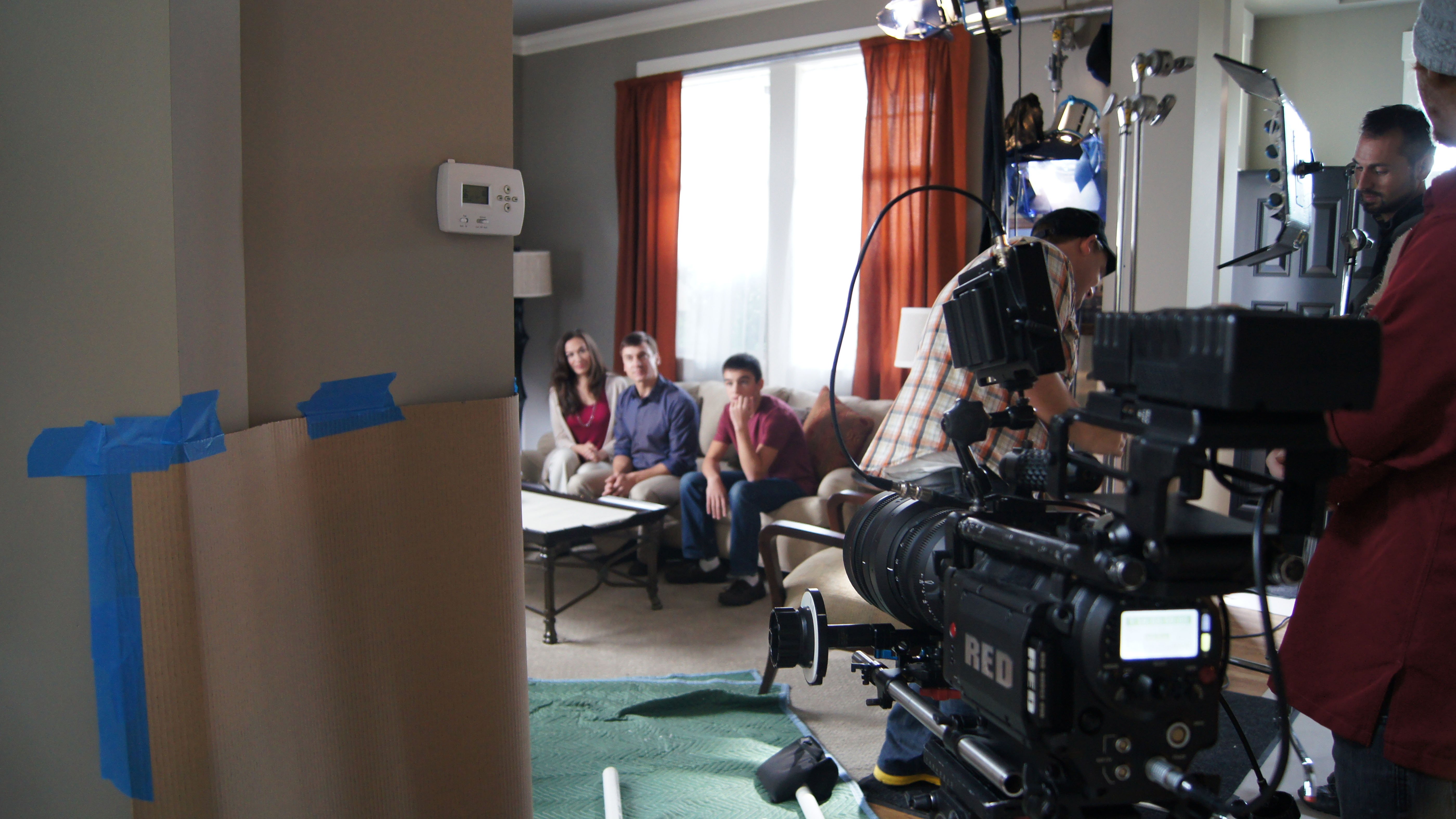 Video production crew filming two parents and a child in a living room setting