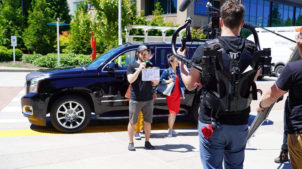 Video production company filming live-action video outside in front of a car