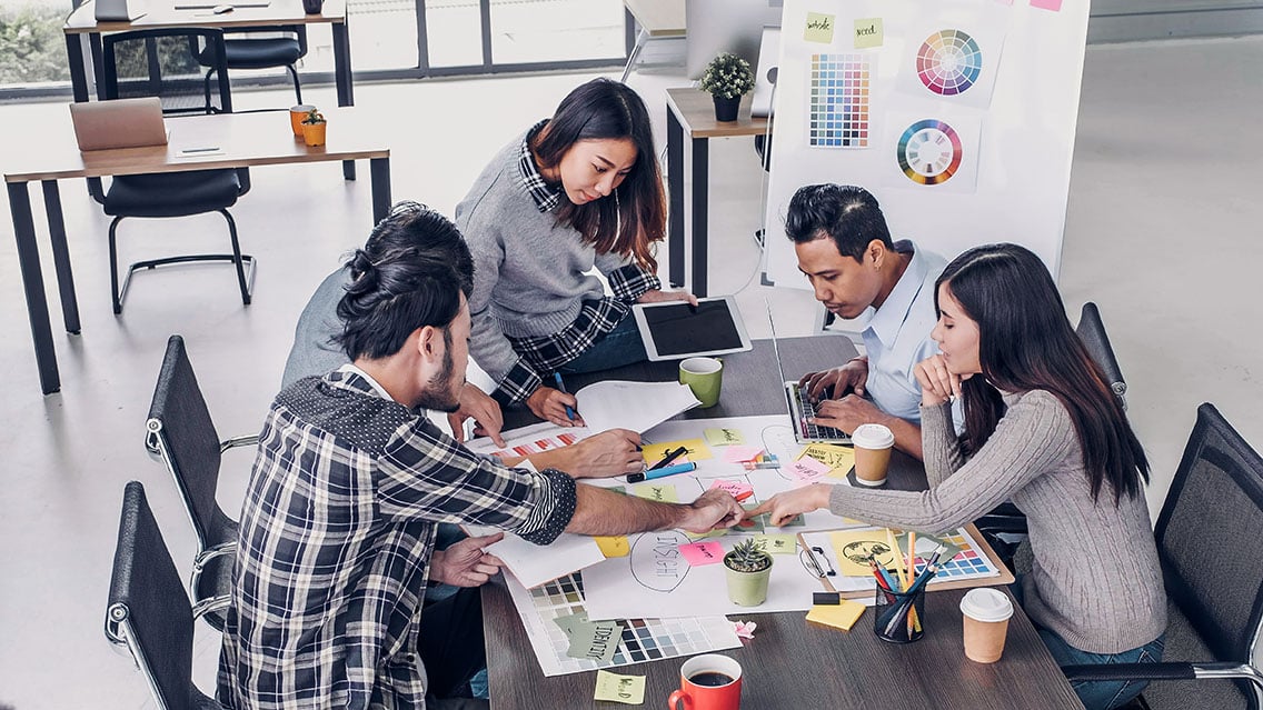 Group of marketers at a table working on creating their brand essence in a nicely lit office space