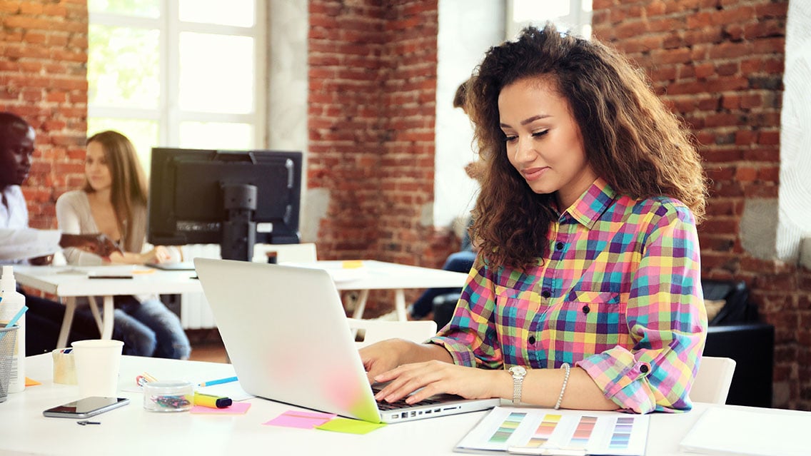 Woman sitting at a desk looking at her laptop for content marketing purposes